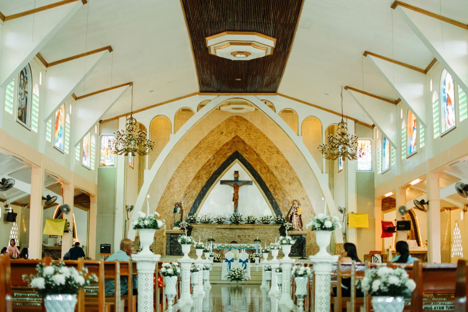 The sanctuary of a bright church, with a crucifix above the altar framed by a tall arch
